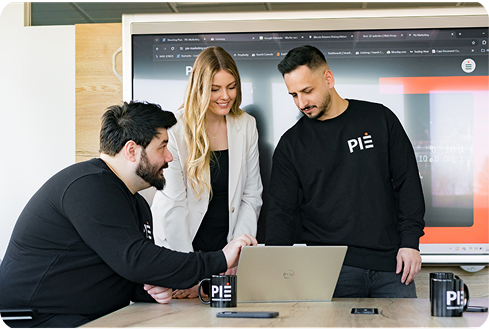 Drei Teammitglieder von der Werbeagentur PIE Marketing bei der kreativen Zusammenarbeit am Tisch