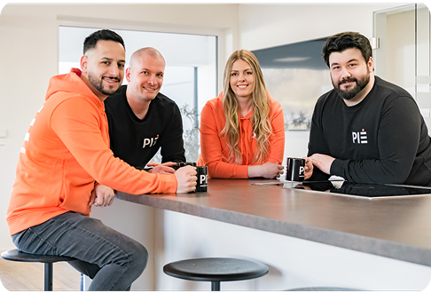 Vier PIE Marketing Teammitglieder am Tisch mit PIE-Tassen 