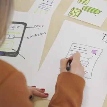 Frau skizziert Website-Layout am Tisch, individuelle Homepage und Webdesign für Unternehmen